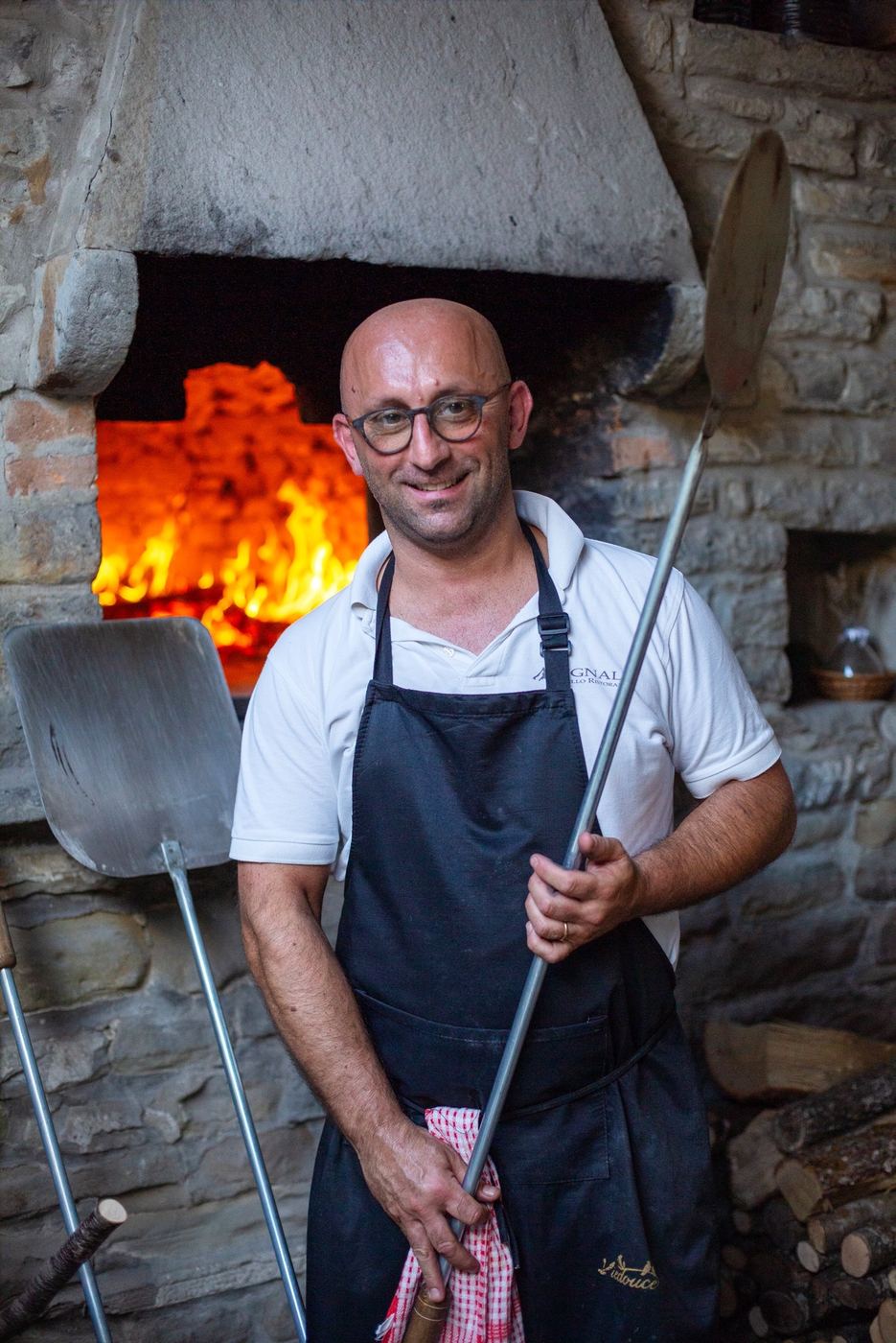 Il cuoco in grembiule davanti al forno a legna acceso