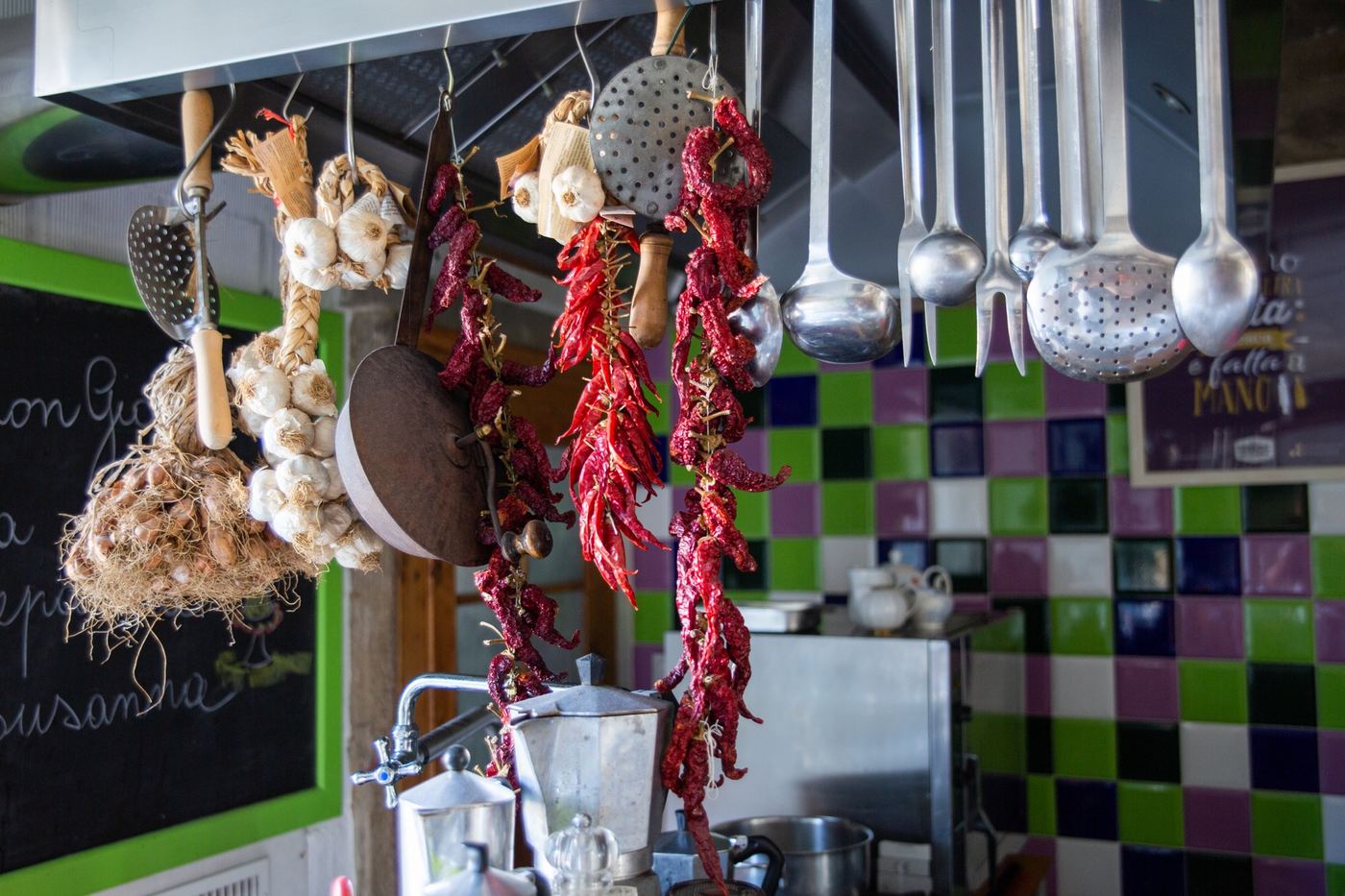Dettaglio della cucina: peperoncini e utensili appesi, piastrelle colorate