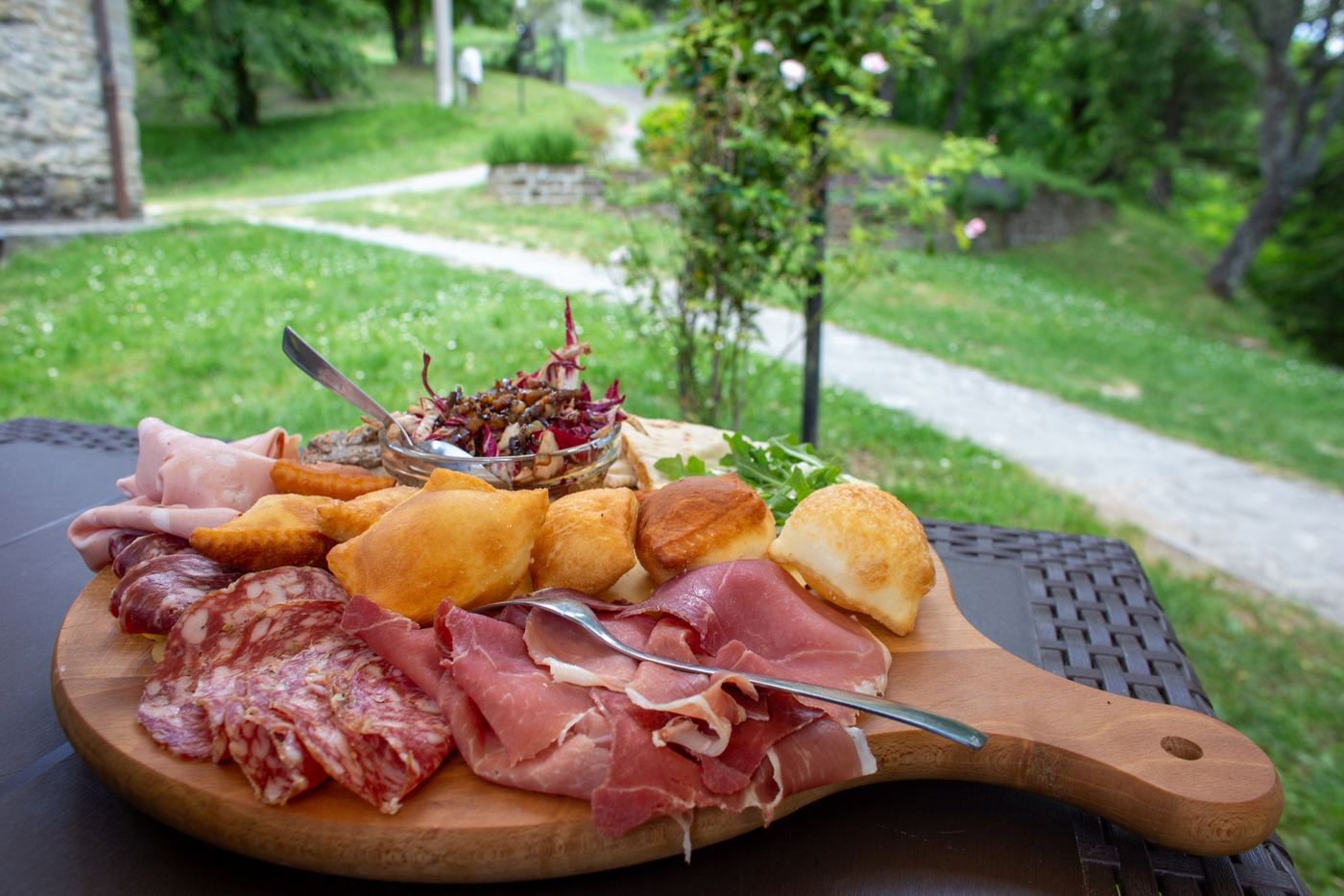 Tagliere di salumi e pane fritto su un tavolo in giardino