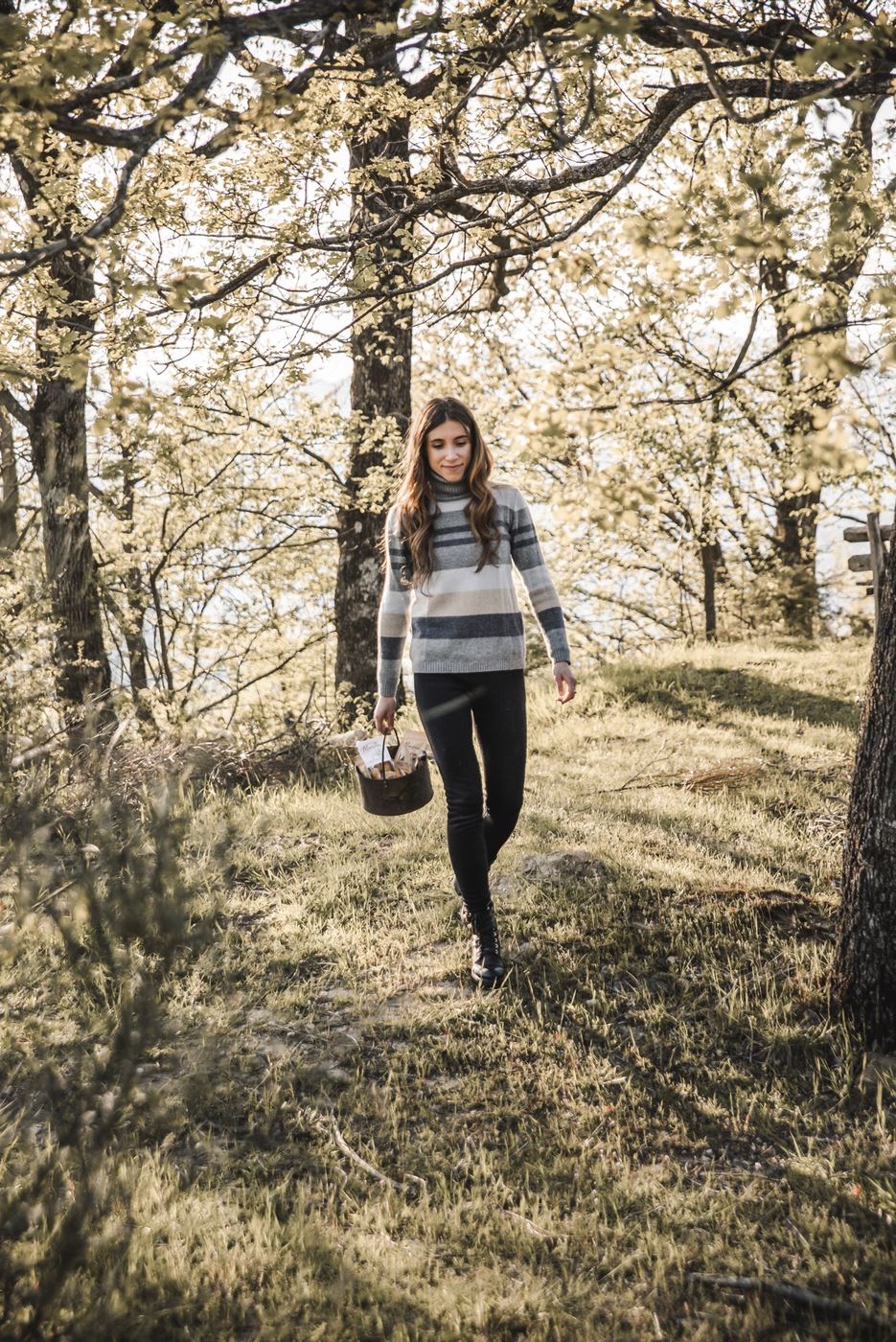 Una donna cammina nel bosco con un cesto