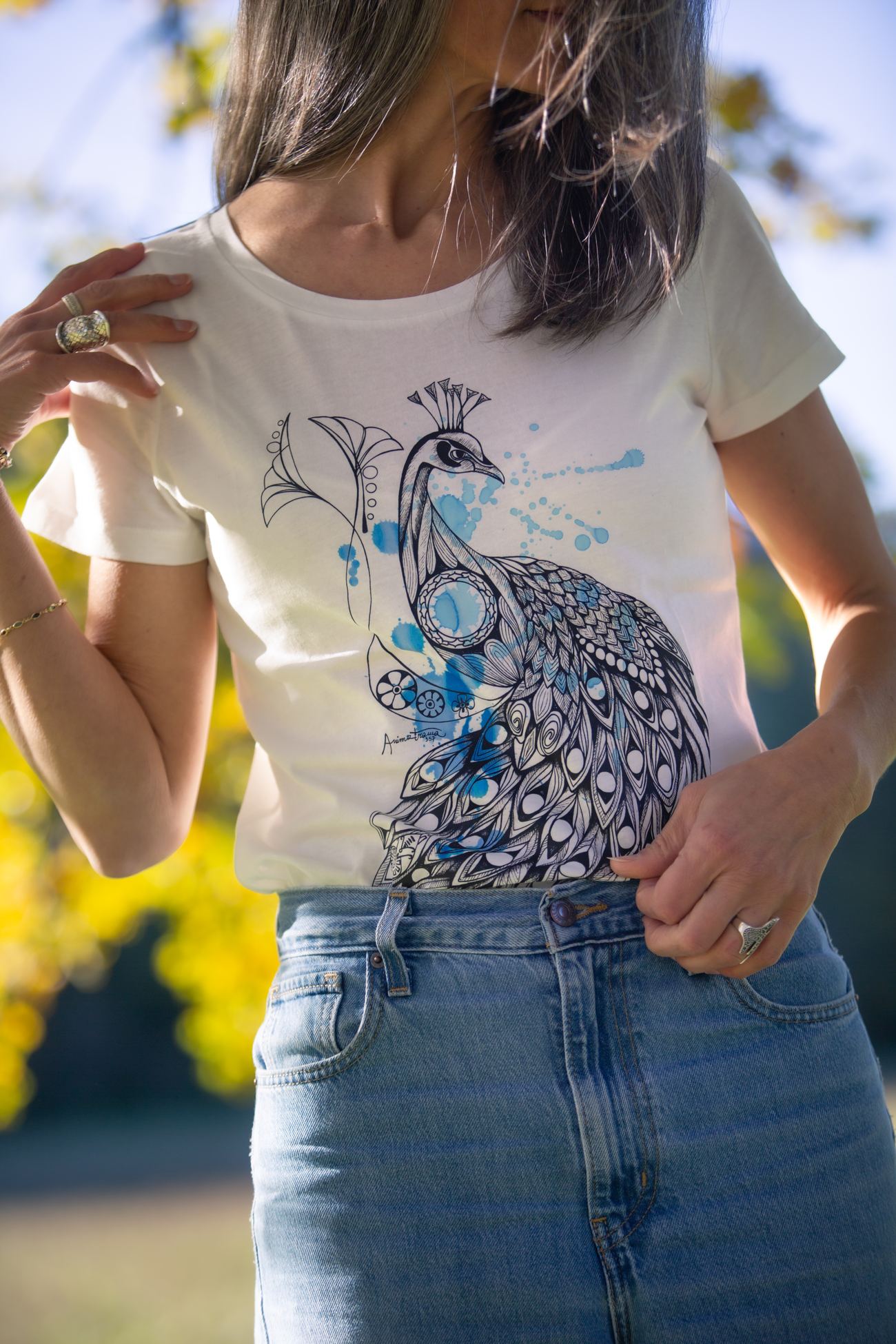 Maglietta con il pavone disegnato a mano, indossata nel giardino