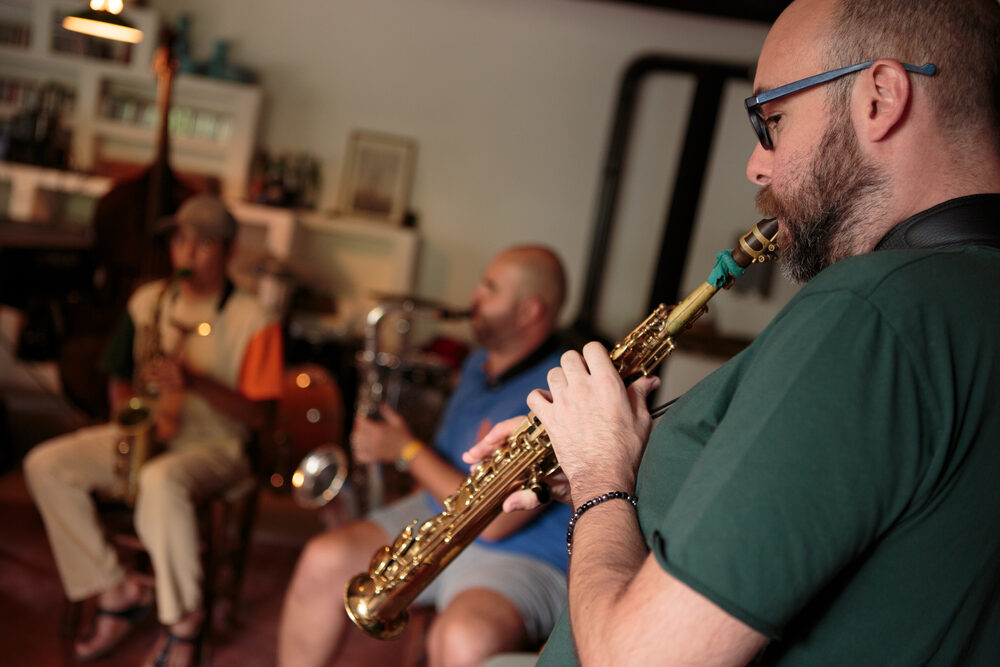 Musicista al sax soprano durante la lezione, con il quartetto sullo sfondo