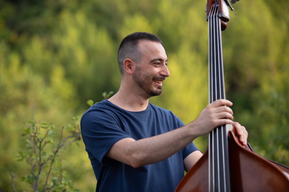 Contrabbassista sorridente tra il verde